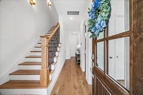 a view of a hallway with wooden floor and stairs