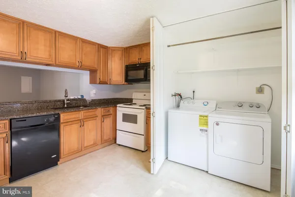 a kitchen with granite countertop a refrigerator a sink and a stove