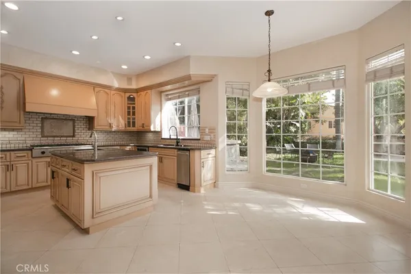 a kitchen with stainless steel appliances granite countertop a stove top oven a sink and a chandelier