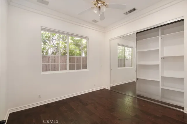 an empty room with wooden floor cabinet and windows