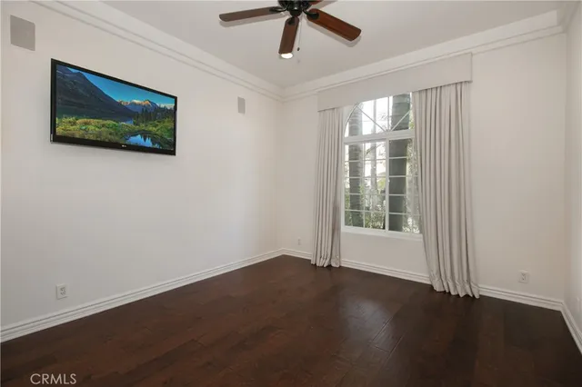 a view of a livingroom with wooden floor a ceiling fan and a window