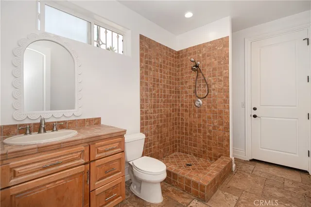 a bathroom with a granite countertop toilet a sink a shower and a mirror