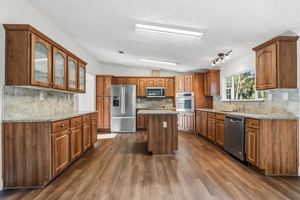 1785 Marsh Way Geneva, FL 32732 - Photo 20 of 40 a kitchen with stainless steel appliances granite countertop wooden cabinets a stove top oven a sink and dishwasher