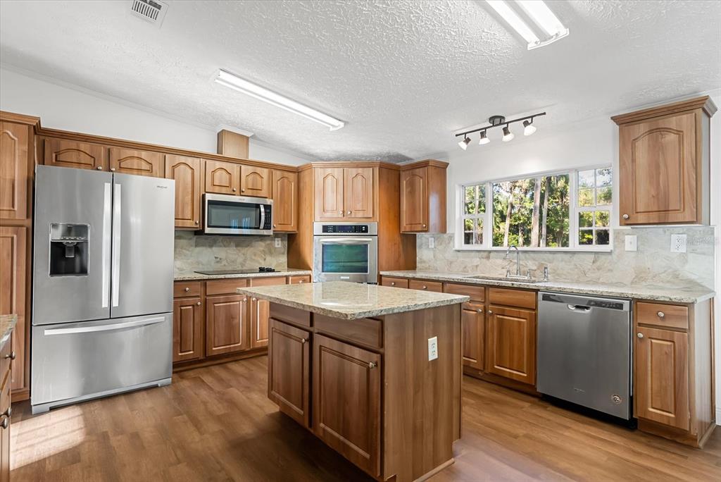 1785 Marsh Way Geneva, FL 32732 - Photo 21 of 40 a kitchen with stainless steel appliances granite countertop a stove a sink dishwasher a refrigerator and a microwave oven with wooden floor