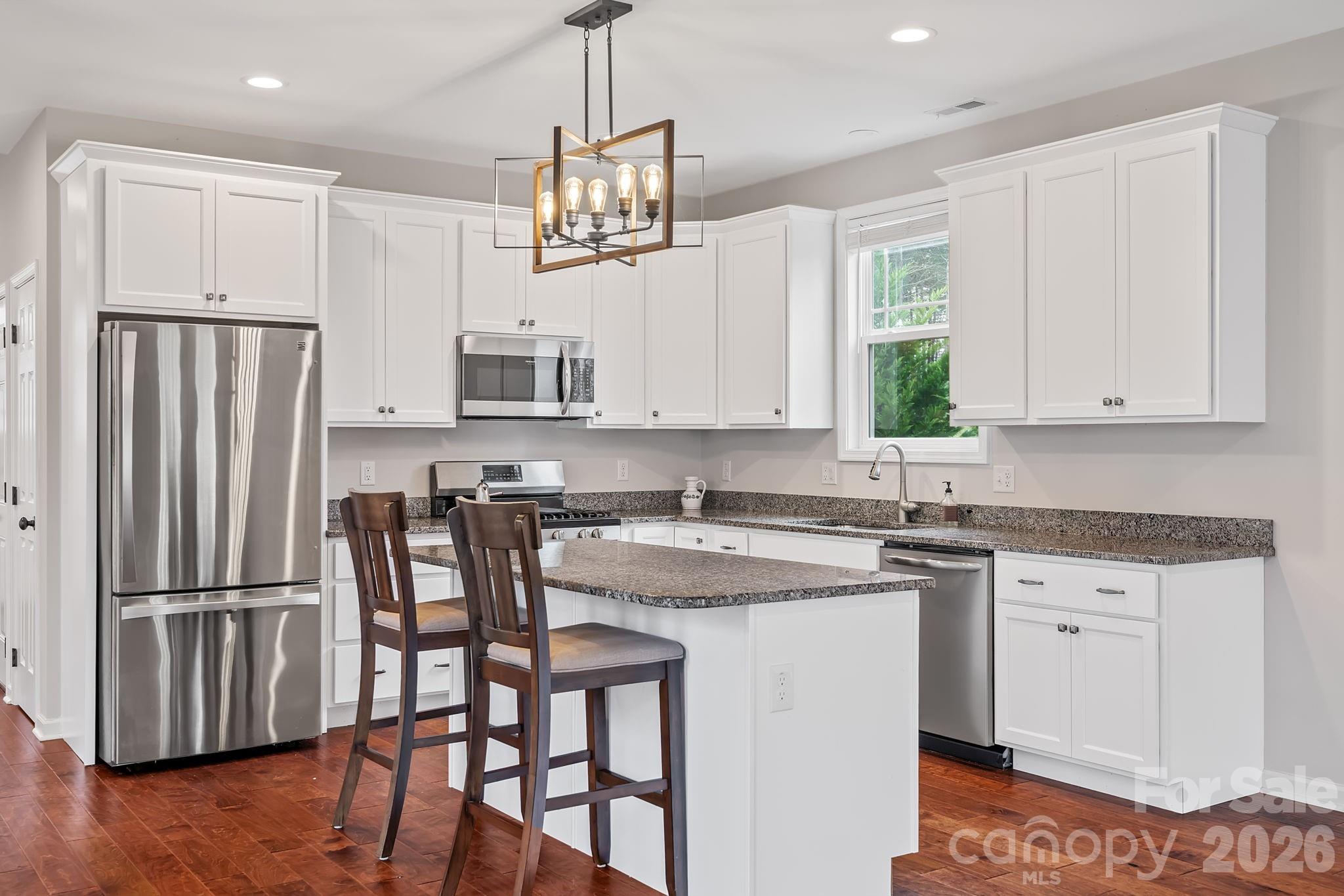 57 Parrot Road Candler, NC 28715 - Photo 8 of 44 a kitchen with stainless steel appliances granite countertop a stove a refrigerator a sink dishwasher a dining table and chairs with wooden floor