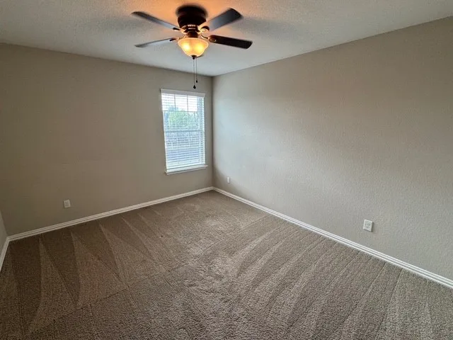 an empty room with windows and fan