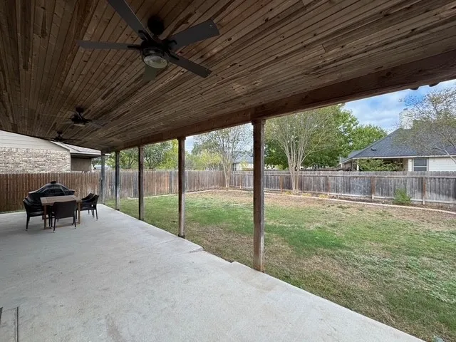 a view of a backyard with couches plants and large trees
