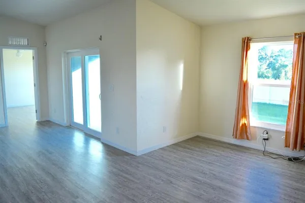 an empty room with wooden floor and windows