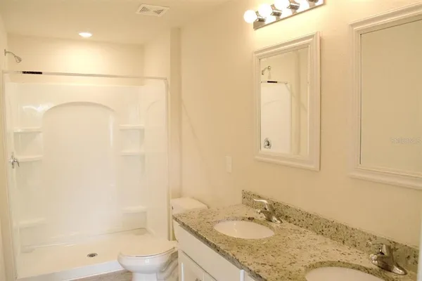 a bathroom with a granite countertop sink a toilet and shower