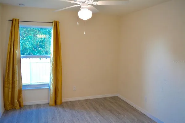 a view of an empty room with wooden floor and a window