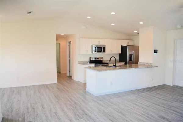 a room with kitchen island stainless steel appliances a sink a refrigerator and cabinets