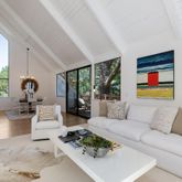 a living room with furniture large windows and wooden floor
