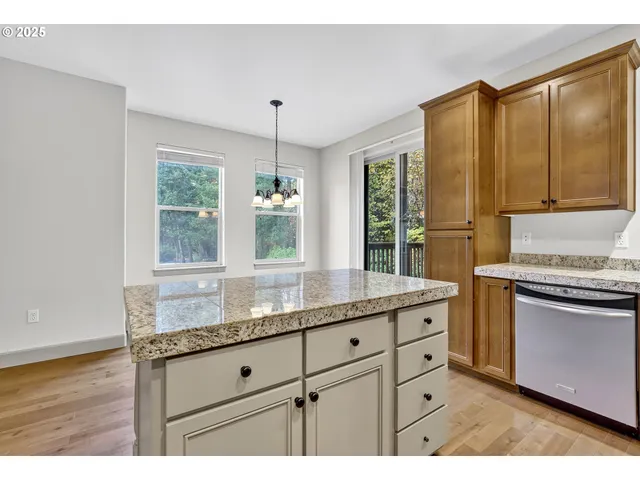 a kitchen with stainless steel appliances granite countertop a stove top oven a sink dishwasher and white cabinets with wooden floor