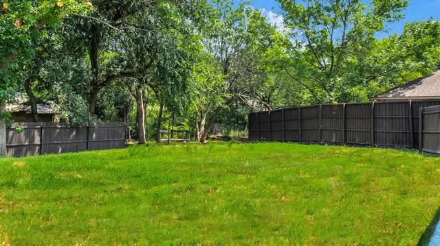 a view of backyard with a table and chairs and a large tree