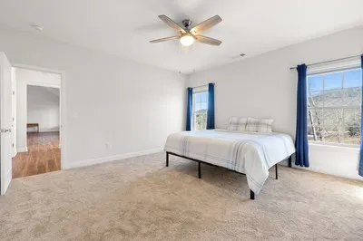 a view of an empty room with a window and a chandelier fan
