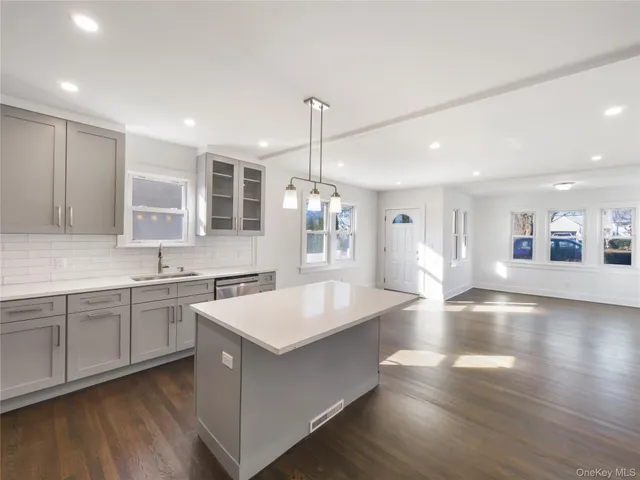 a large kitchen with kitchen island a stove a sink a center island and wooden floor