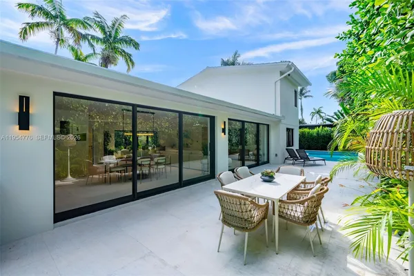 a view of a patio with table and chairs potted plants and floor to ceiling window