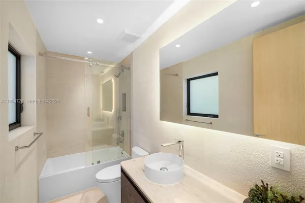 a bathroom with a bathtub shower sink mirror and toilet