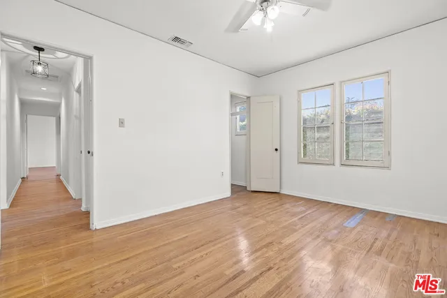 an empty room with chandelier fan and windows