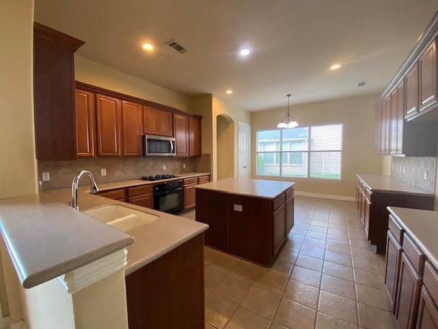 4952 Stephanie Street Frisco, TX 75033 - Photo 7 of 21 a large kitchen with stainless steel appliances wooden cabinets a stove and a sink