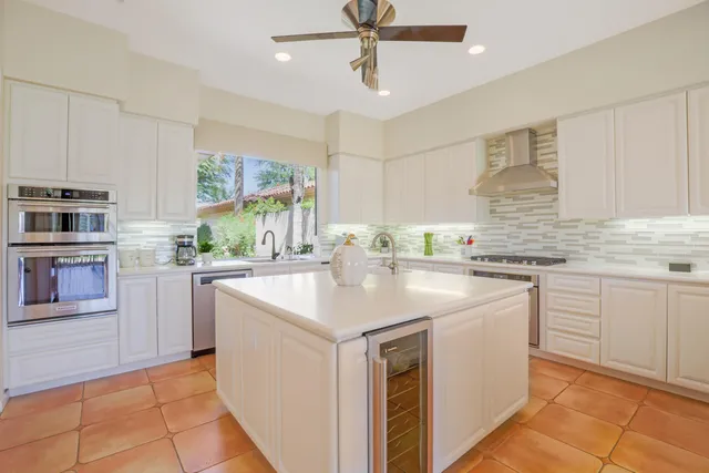 a kitchen with kitchen island granite countertop a sink appliances cabinets and furniture