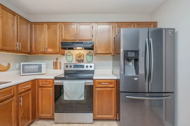 a kitchen with stainless steel appliances granite countertop a refrigerator a stove and a sink