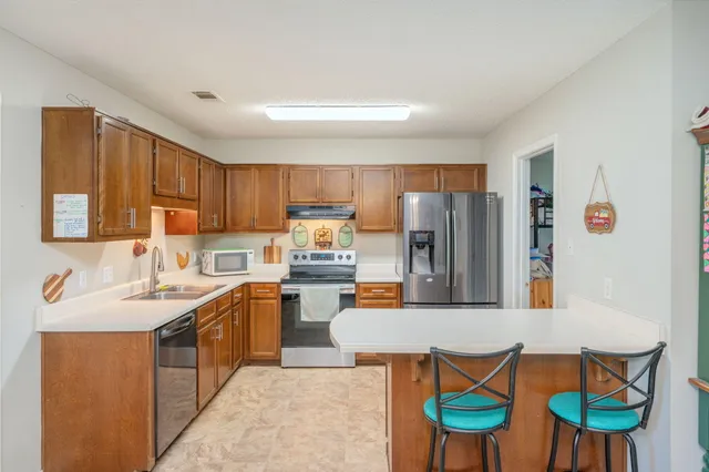 a kitchen with stainless steel appliances granite countertop a refrigerator a stove and a sink