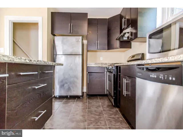 a kitchen with stainless steel appliances granite countertop a refrigerator and a stove