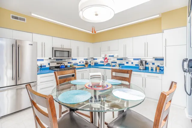 a kitchen with stainless steel appliances granite countertop a dining table and chairs