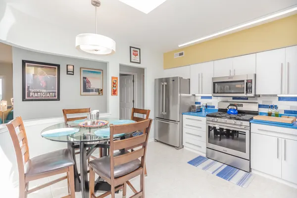 a kitchen with stainless steel appliances granite countertop a dining table chairs refrigerator and microwave