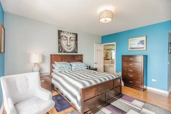 a bedroom with a bed and dresser with wooden floor