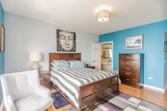 a bedroom with a bed and dresser with wooden floor