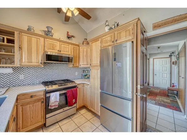 a kitchen with stainless steel appliances granite countertop a refrigerator a stove and a sink with wooden cabinets