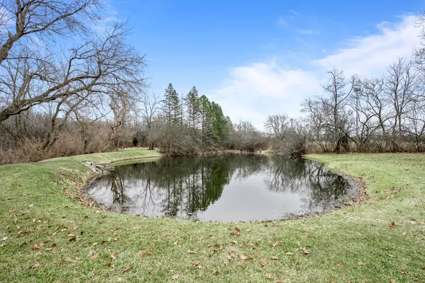 a view of a lake with a yard and large trees