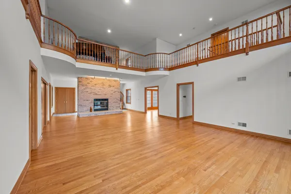 a view of an empty room with wooden floor and a fireplace