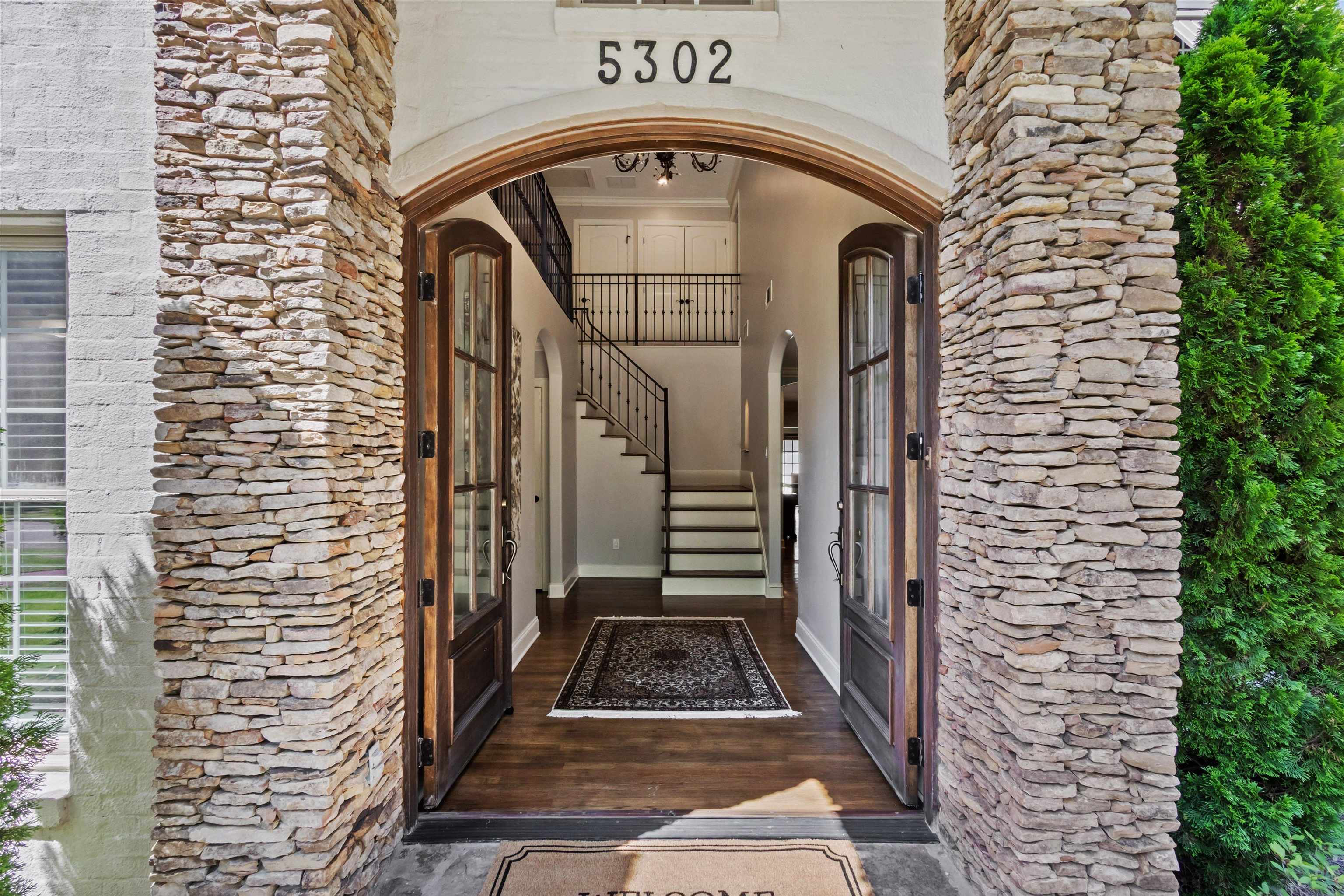 5302 South Angela Road Memphis, TN 38120 - Photo 38 of 40 Stone-clad entry columns framing an arched doorway with dark wood-finish French doors