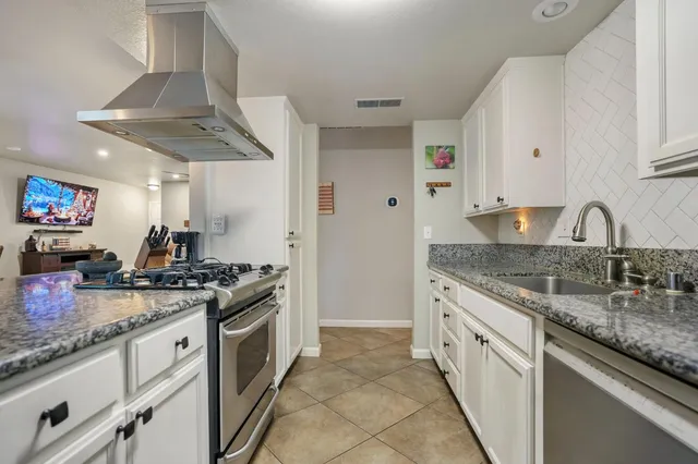 a kitchen with granite countertop a sink stove and cabinets