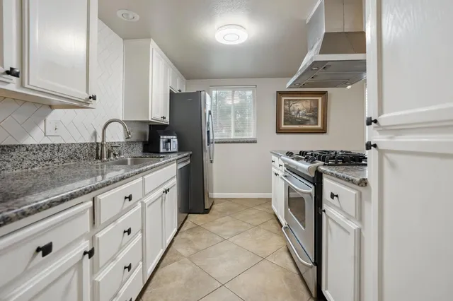 a kitchen with granite countertop a sink stove and cabinets