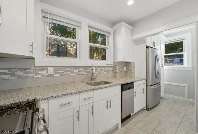 a kitchen with stainless steel appliances granite countertop a sink and a refrigerator