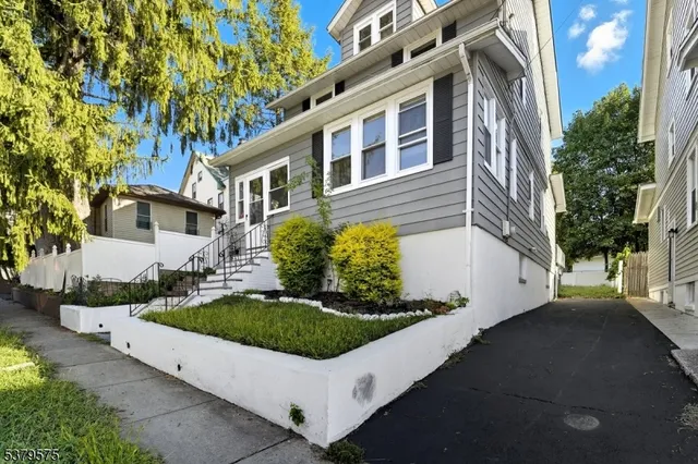 a view of a white house with a big yard and large tree