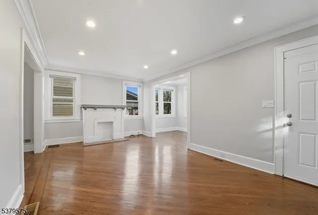 a view of empty room with wooden floor and kitchen
