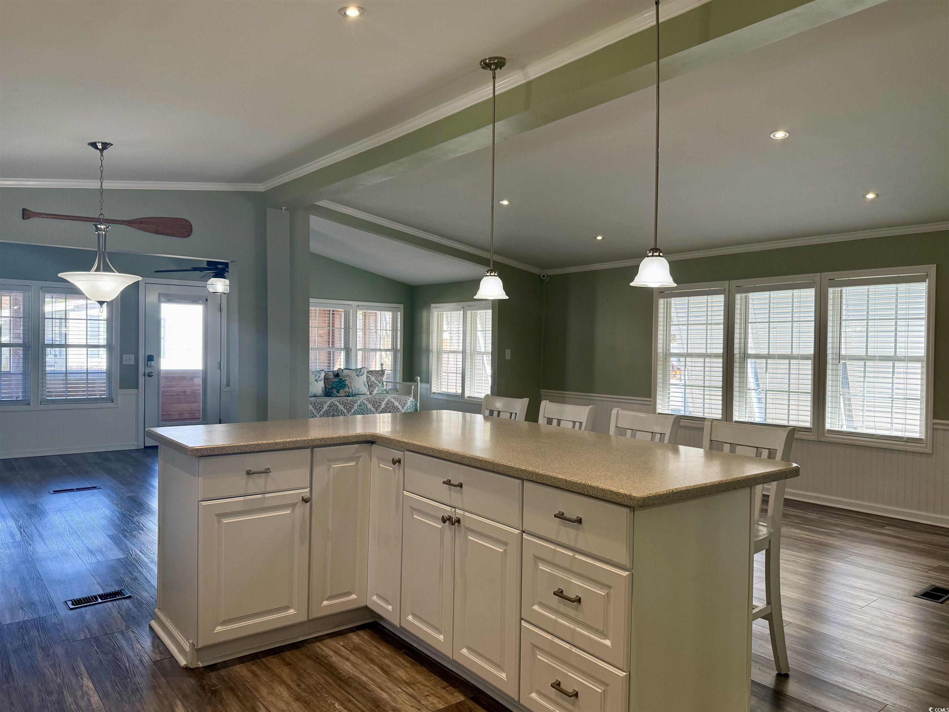 465 Sandpebble Surfside Beach, SC 29575 - Photo 38 of 40 Kitchen featuring a breakfast bar area, white cabinets, open floor plan, crown molding, and dark wood finished floors