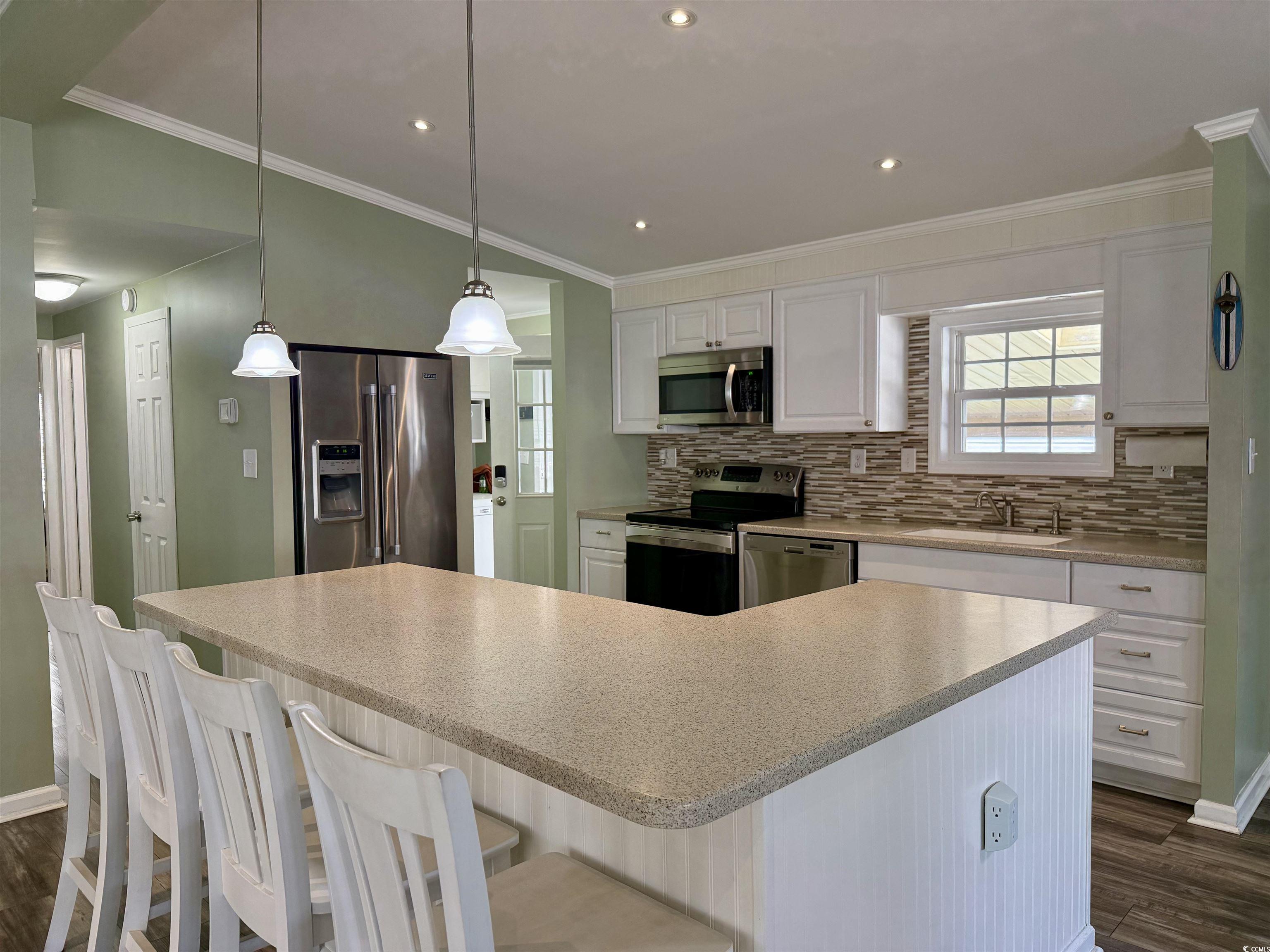 465 Sandpebble Surfside Beach, SC 29575 - Photo 5 of 40 Kitchen with white cabinetry, appliances with stainless steel finishes, crown molding, dark wood finished floors, and pendant lighting