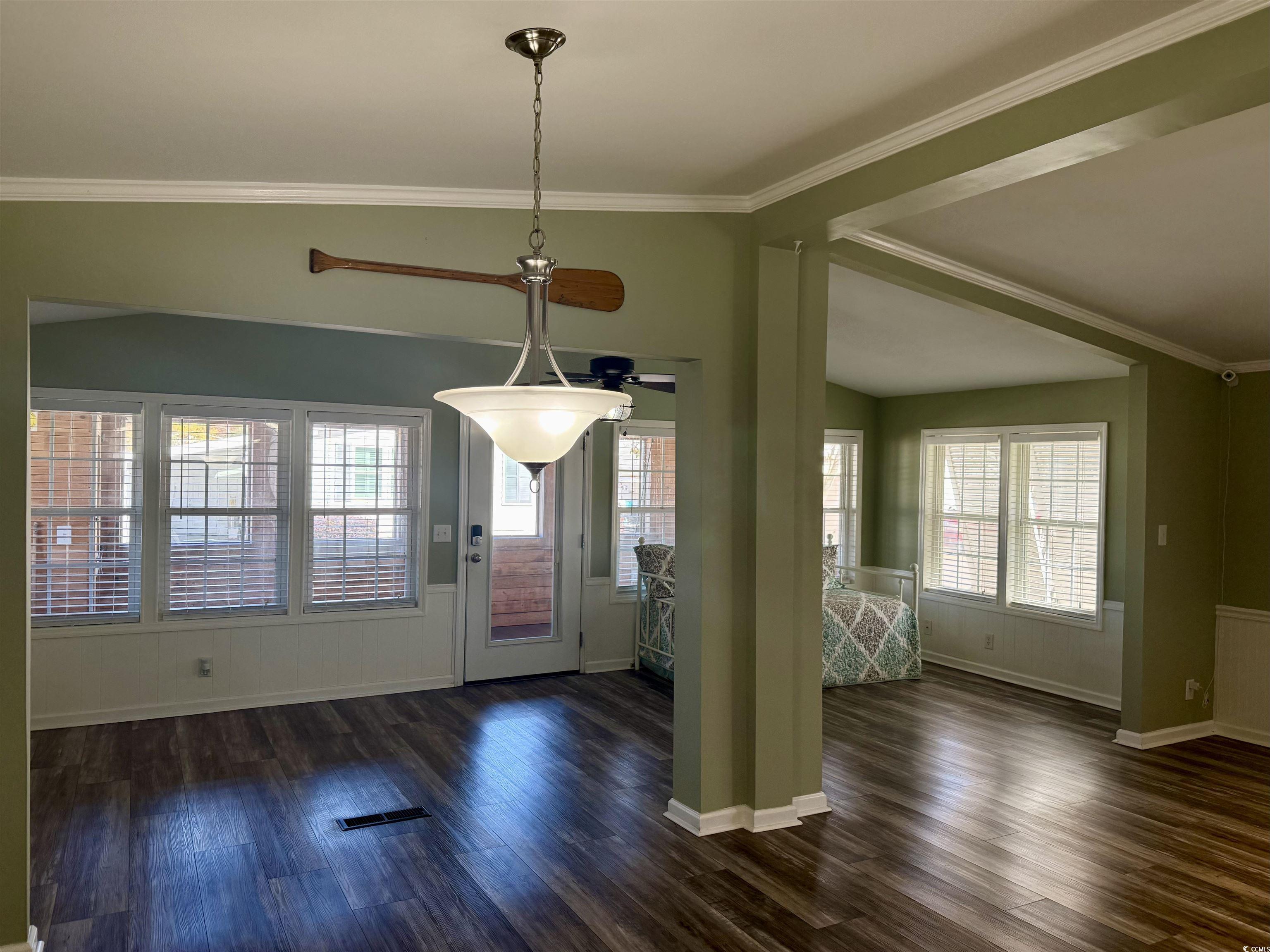 465 Sandpebble Surfside Beach, SC 29575 - Photo 7 of 40 Unfurnished dining area featuring crown molding, vaulted ceiling, dark wood-style floors, a wainscoted wall, and ceiling fan