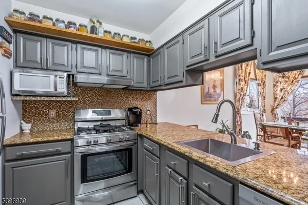 a kitchen with granite countertop a sink a stove and cabinets