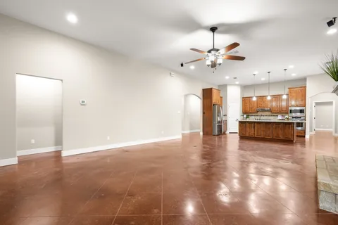 an empty room with wooden floor fireplace and chandelier