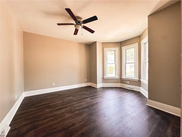 an empty room with wooden floor and windows