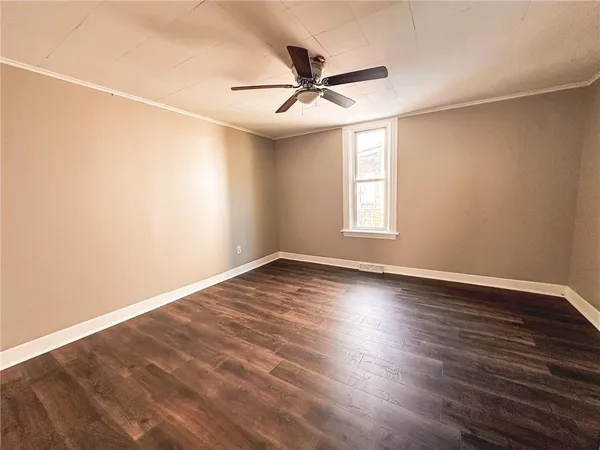 an empty room with wooden floor fan and windows