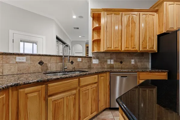 a kitchen with granite countertop wooden cabinets a sink and dishwasher