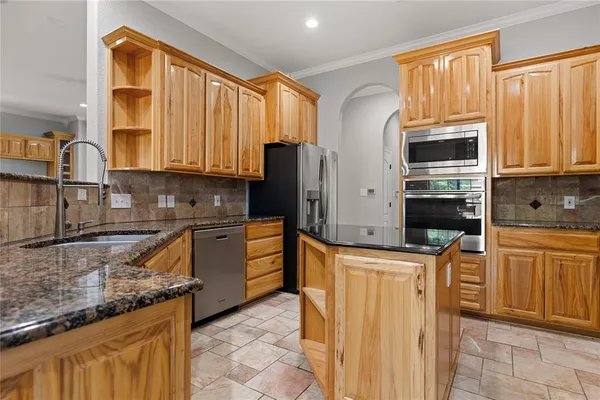 a kitchen with stainless steel appliances granite countertop a stove a sink dishwasher and a refrigerator